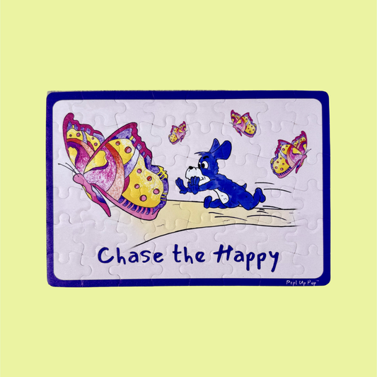 Children's puzzle with a cartoon purple dog, Prpl Up Pup, chasing butterflies and 'Chase the Happy' text on a beige background.