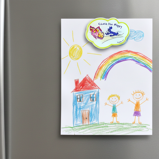 Children's drawing of a house, sun, rainbow, and two children on a refrigerator and the "Chase the Happy" magnet is attached to the fridge. The illustration on the magnet is inspired by the world of Prpl Up Pup.