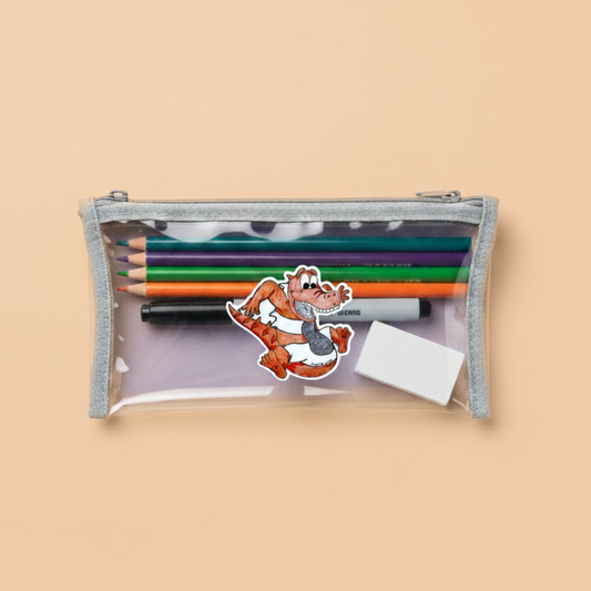 Clear pencil case with colorful pencils and a cartoon crocodile character on a light orange background. This sticker is inspired by the world of Prpl Up Pup.