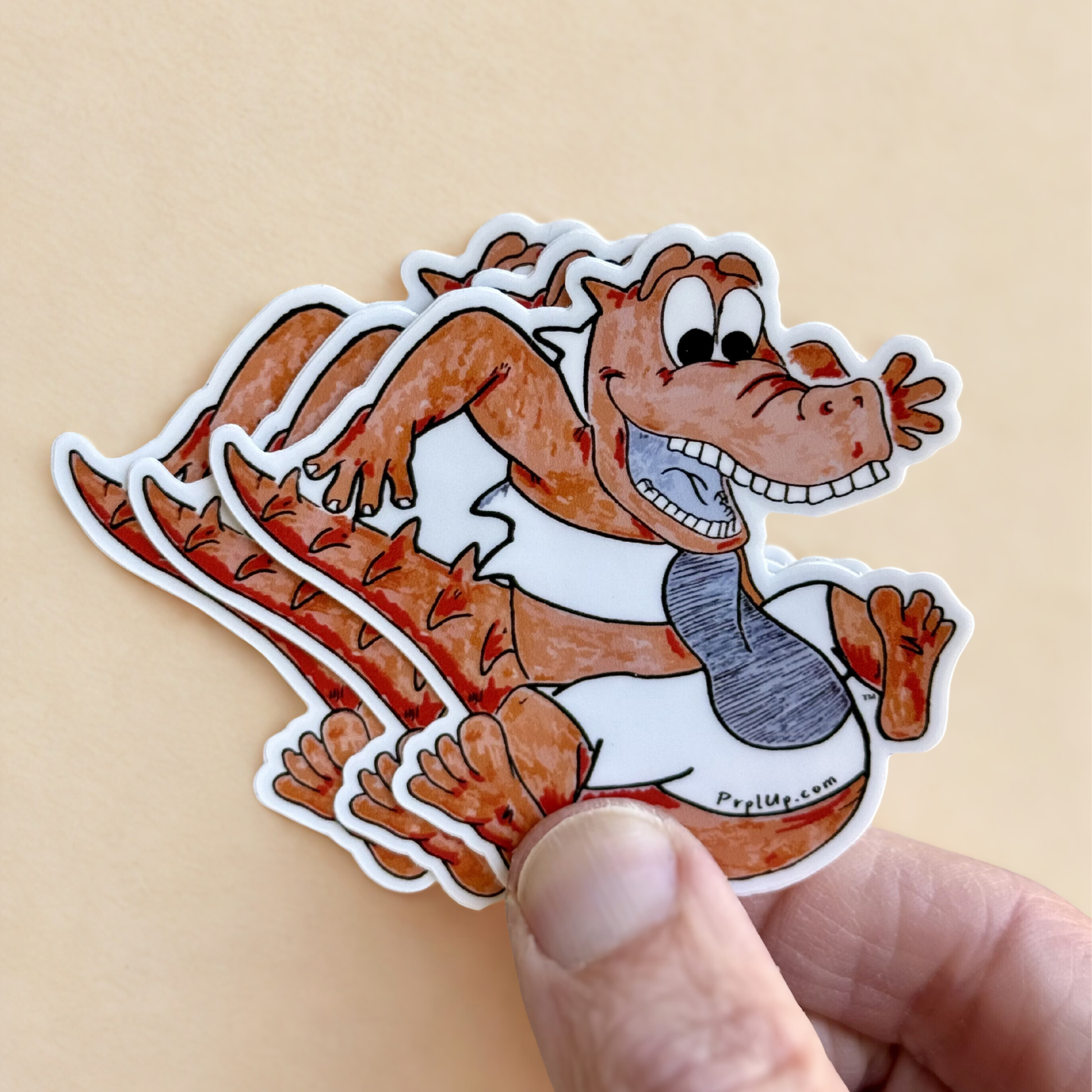 Hand holding a cartoon crocodile, Luther, sticker with a light orange background. This sticker is inspired by the world of Prpl Up Pup.