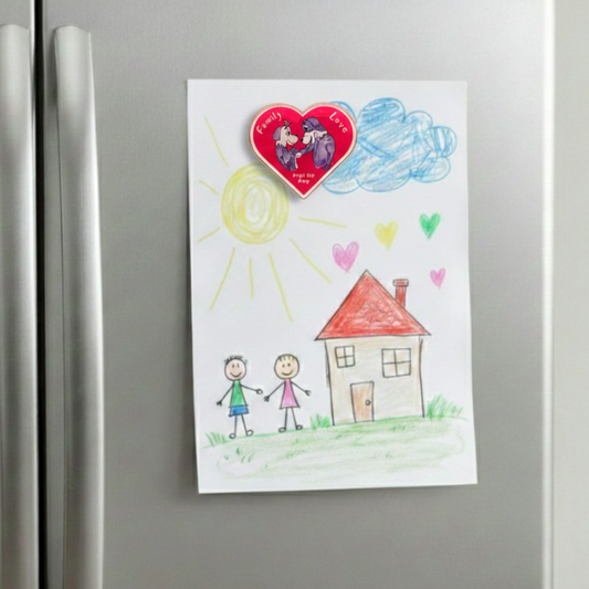 Colorful drawing of a house, heart, and children on a refrigerator. The Pup Love Magnet is holding the drawing sheet. 