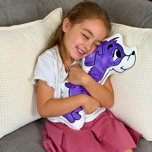 Young girl hugging a purple cartoon dog pillow on a couch